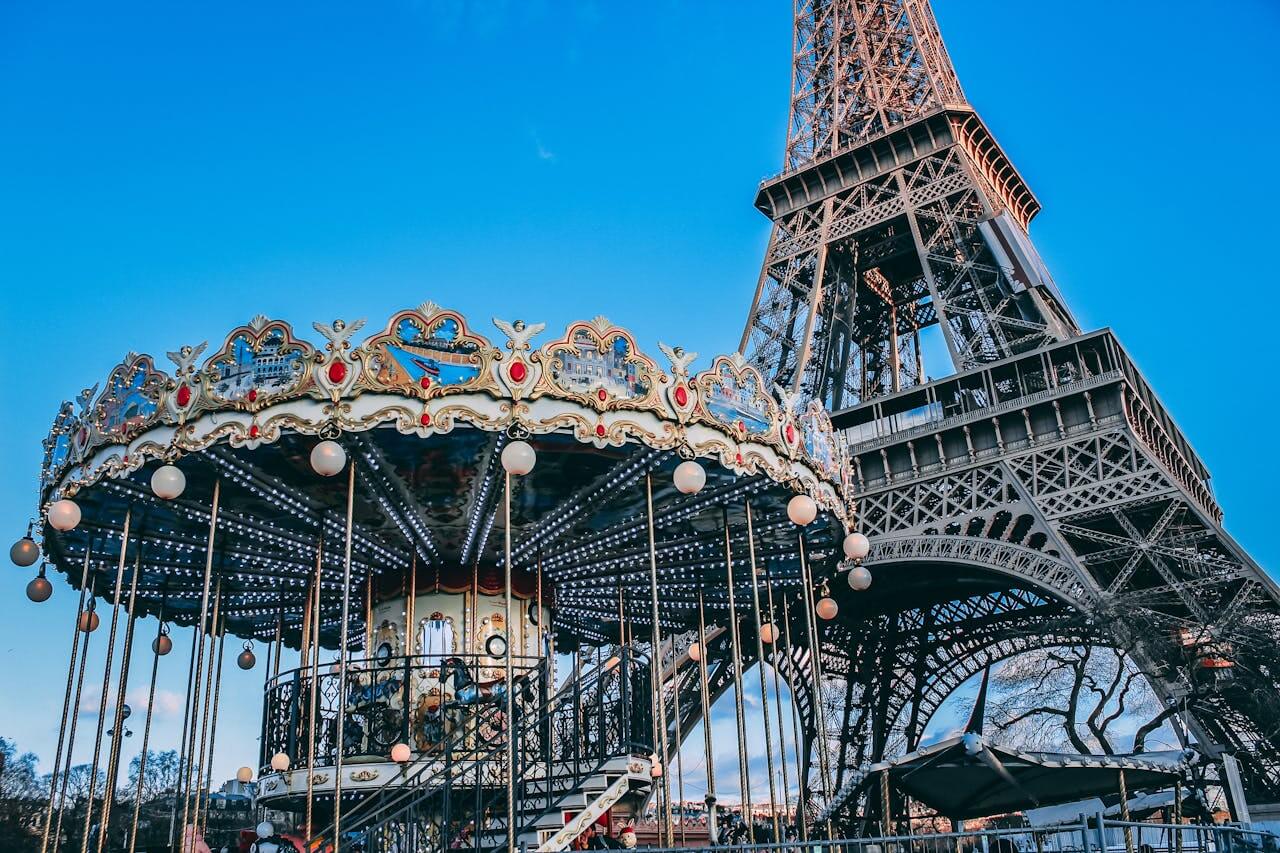 Promenades à Paris Eiffel Tower with a classic carousel in foreground on a bright day in Paris, France.